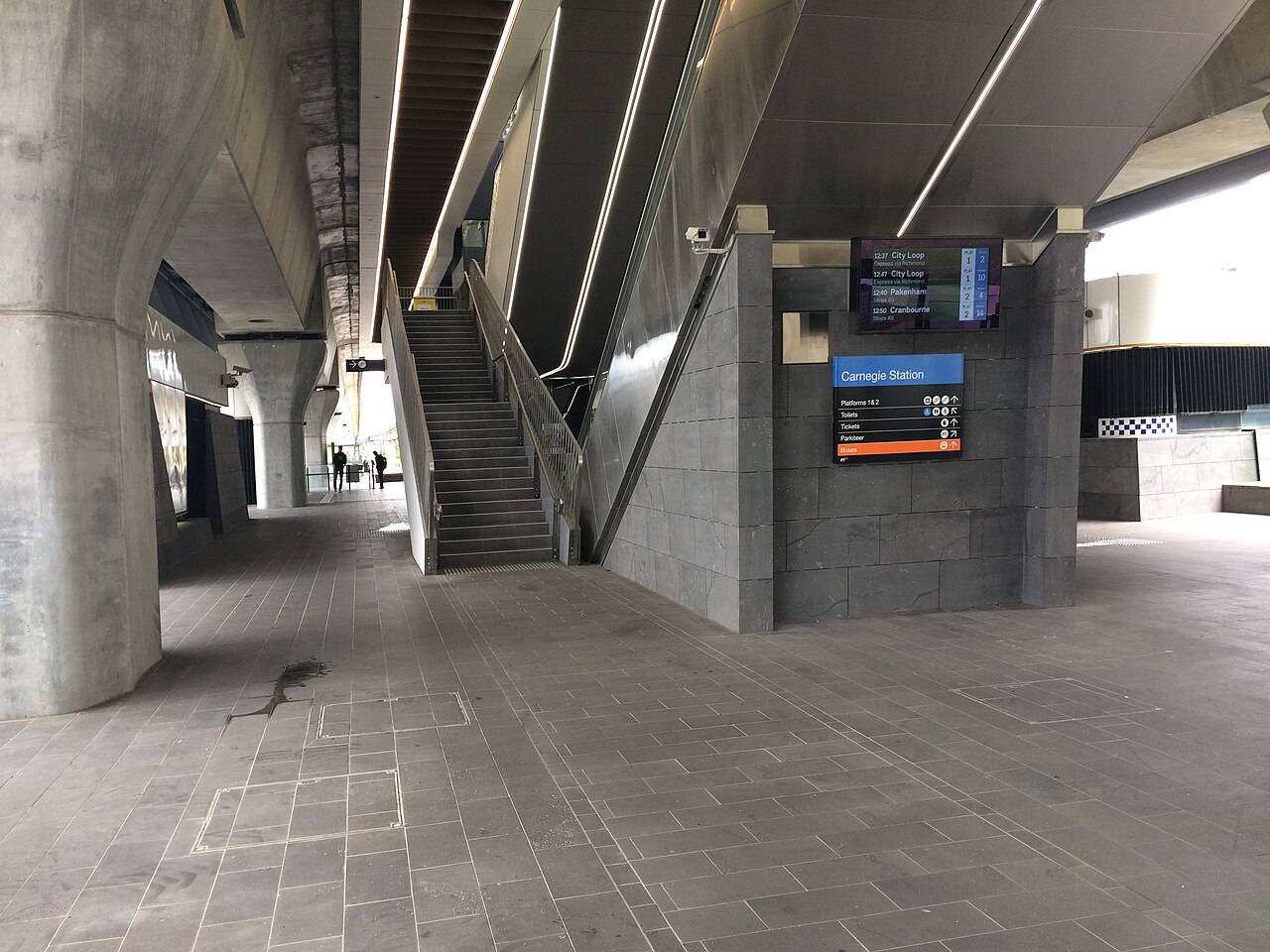 The concourse under Carnegie railway station with its stairs, escalator and Carnegie Station sign