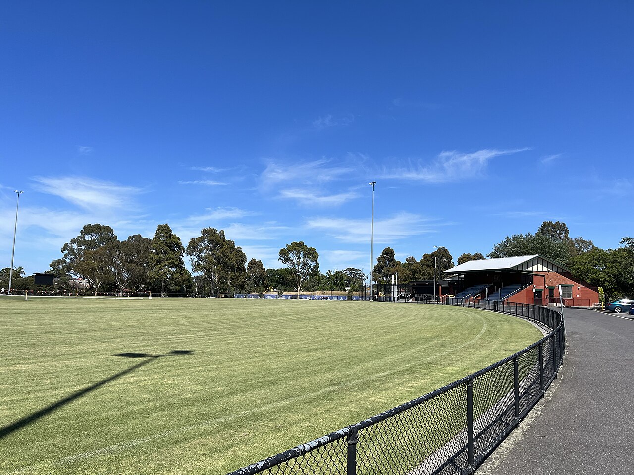 The oval and red-brick pavilion at Koornang Park, Carnegie, under a blue sky