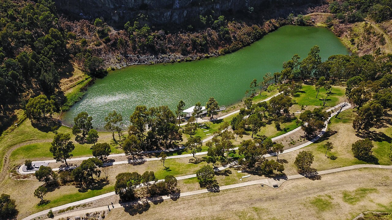 Aerial view of a green quarry lake surrounded by parkland