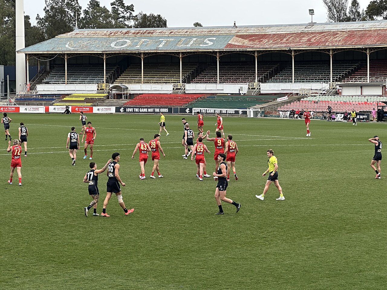 Football match on the oval in front of a heritage grandstand