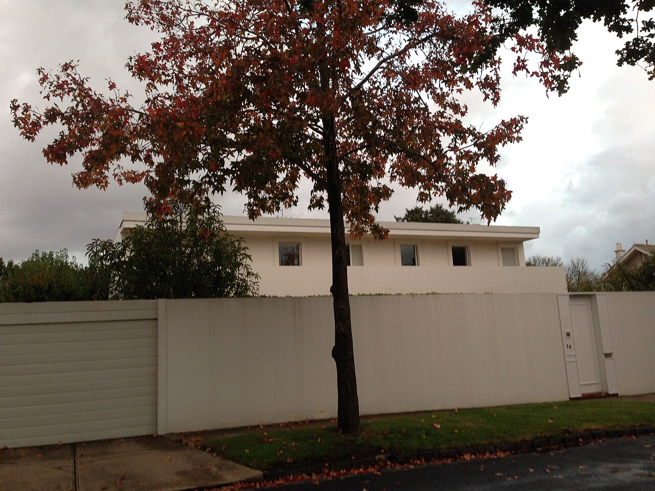 Clemenger House behind a high white wall and autumn tree