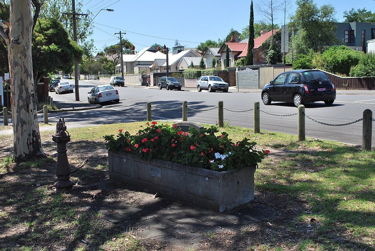 Historic horse trough with flowers on a suburban street