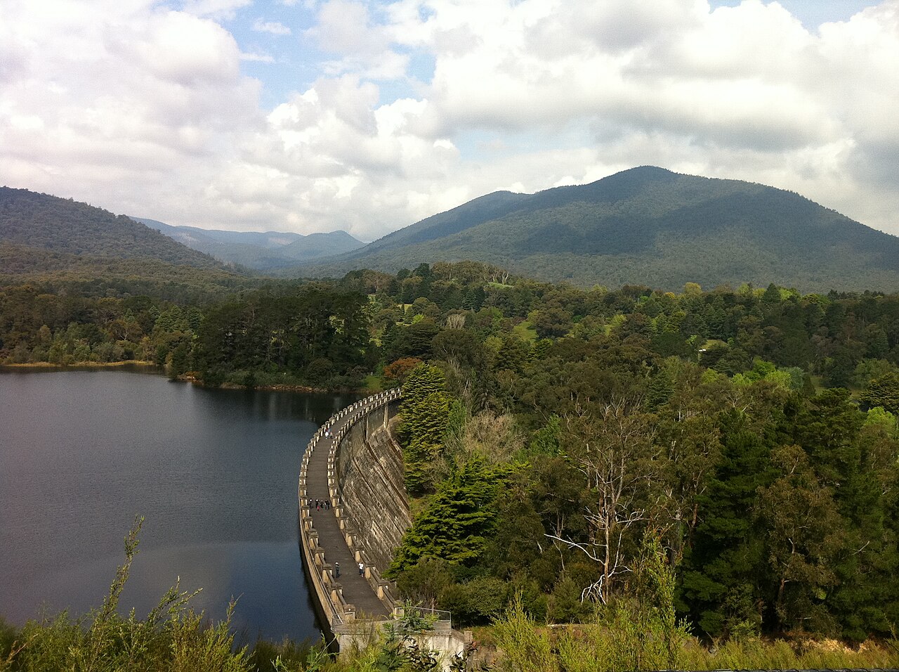 Maroondah Dam at capacity with forested mountains behind