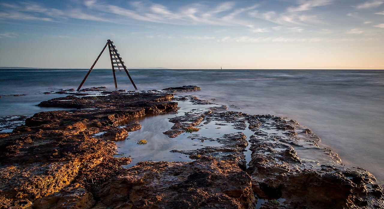 Navigation beacon on a rocky shore at sunset