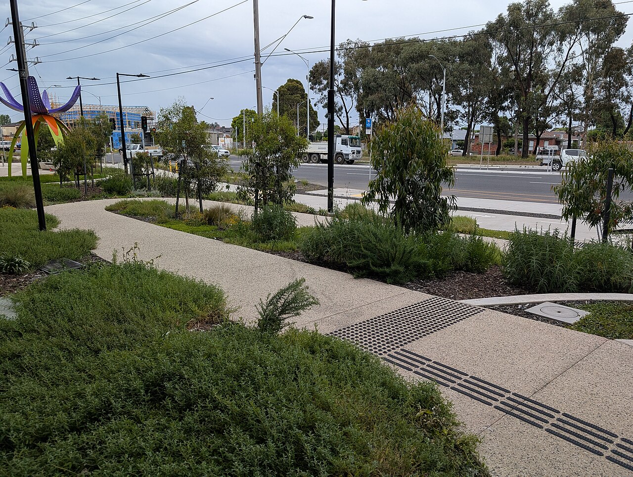 Winding landscaped path beside the elevated rail line near Keon Park