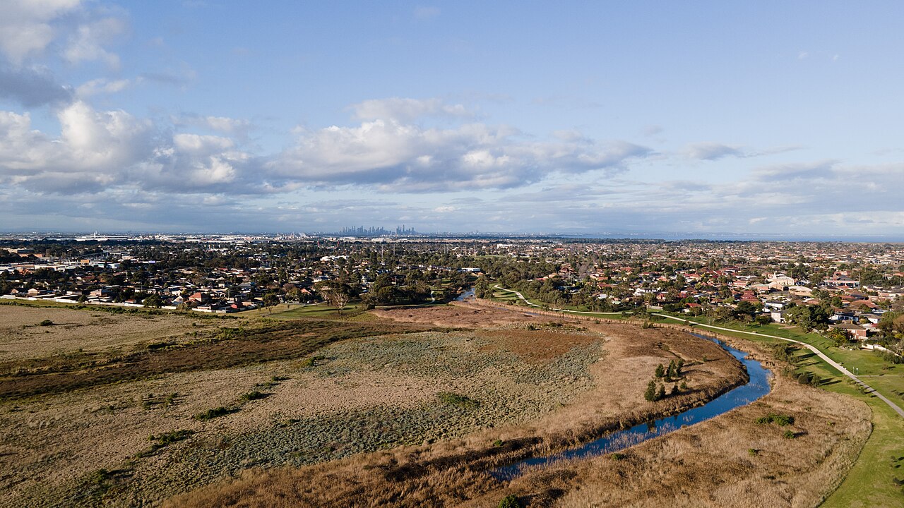 Skeleton Creek winding through grassland with the Melbourne skyline on the horizon