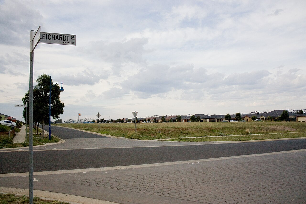A new street corner with open land beyond in a growing estate