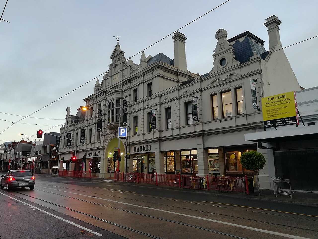 The heritage facade of Prahran Market on Commercial Road at dawn, with tram wires overhead
