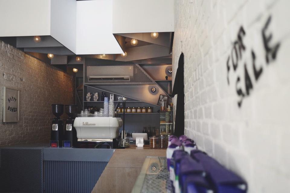 A small cafe seen from the door: counter, machine and a few tables